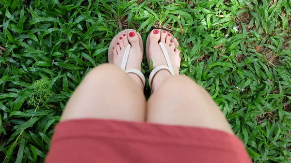 在绿色草地上穿着凉鞋的女孩的脚上特写 — 图库照片