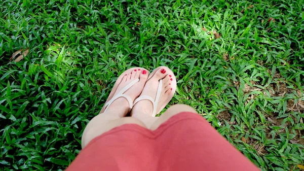 Fermer sur les pieds de la fille portant des sandales sur herbe verte — Photo