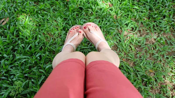 Fermer sur les pieds de la fille portant des sandales sur herbe verte — Photo