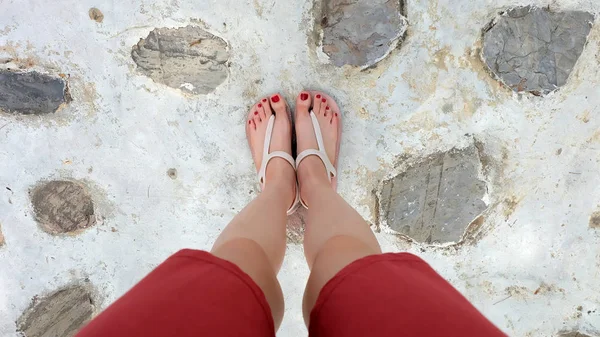 Close Up on Girl\'s Feet Wearing Sandals and Red Nail on The Cement