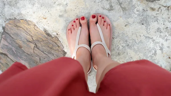Zamknąć na dziewczęce nogi nosić sandały i czerwone paznokci na Cement — Zdjęcie stockowe