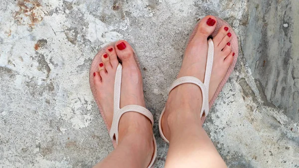 Close Up on Girl 's Feet vestindo sandálias e unhas vermelhas no cimento — Fotografia de Stock