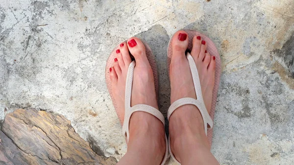 Nahaufnahme an Mädchenfüßen in Sandalen und rotem Nagel auf dem Zement — Stockfoto