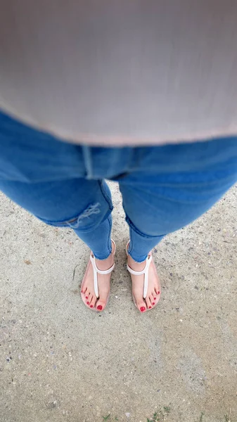Sandalet ve kot üzerinde çimento giyen kızın ayakları üzerinde Kapat