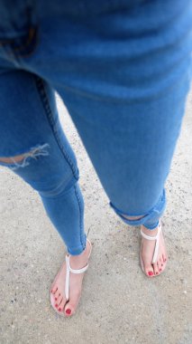 Kutunun üzerinde sandalet ve kot giyen kızın ayakları üzerinde Kapat