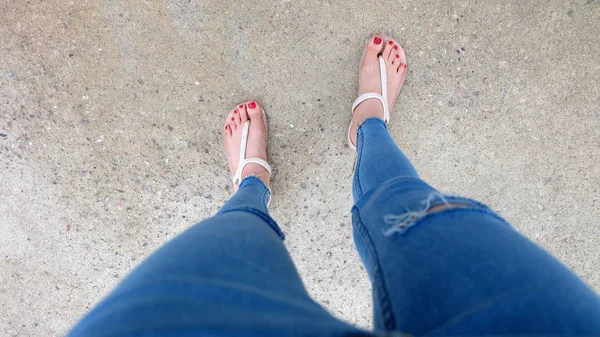 Kutunun üzerinde sandalet ve kot giyen kızın ayakları üzerinde Kapat