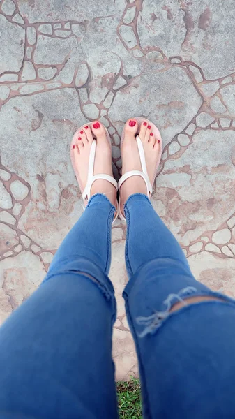 Kutunun üzerinde sandalet ve kot giyen kızın ayakları üzerinde Kapat