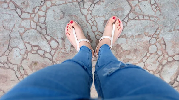 Close Up on Girl 's Feet Wearing Sandals and Blue Jeans on The Tile — стоковое фото