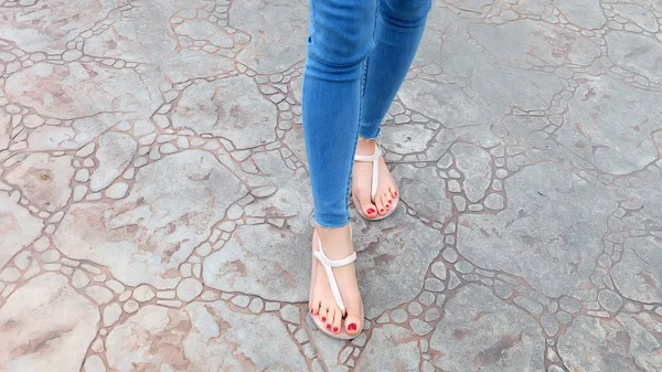 Close Up sui piedi della ragazza indossando sandali e Blue Jeans sulla piastrella — Foto Stock