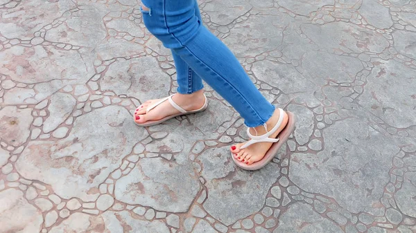 Kutunun üzerinde sandalet ve kot giyen kızın ayakları üzerinde Kapat