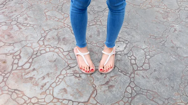 Close Up on Girl 's Feet Wearing Sandals and Blue Jeans on The Tile — стоковое фото