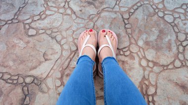 Kutunun üzerinde sandalet ve kot giyen kızın ayakları üzerinde Kapat