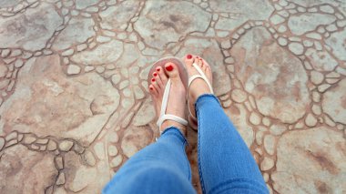 Kutunun üzerinde sandalet ve kot giyen kızın ayakları üzerinde Kapat