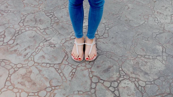 Close Up on Girl 's Feet Wearing Sandals and Blue Jeans on The Tile — Stok Foto