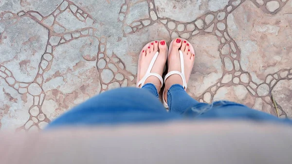 Close-up op meisje voeten dragen sandalen en Blue Jeans op de tegel — Stockfoto