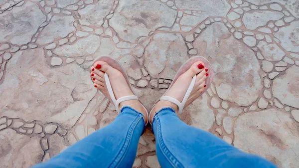 Close Up on Girl 's Feet Wearing Sandals and Blue Jeans on The Tile — стоковое фото