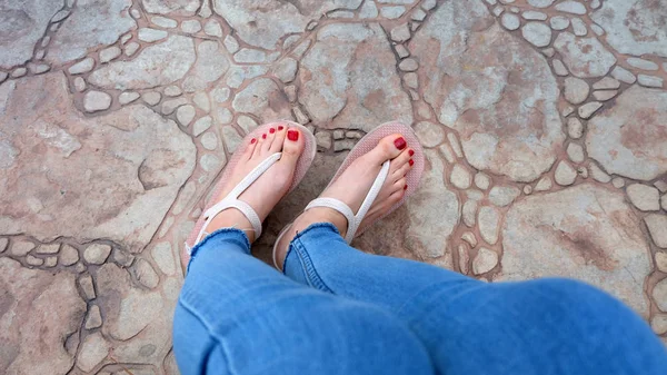 Close-up op meisje voeten dragen sandalen en Blue Jeans op de tegel — Stockfoto