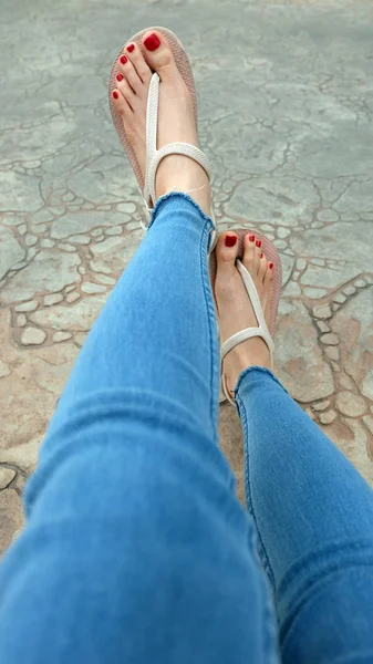 Close Up on Girl 's Feet Wearing Sandals and Blue Jeans on The Tile — стоковое фото