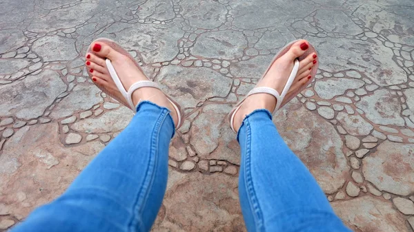 Close Up on Girl 's Feet Wearing Sandals and Blue Jeans on The Tile — стоковое фото