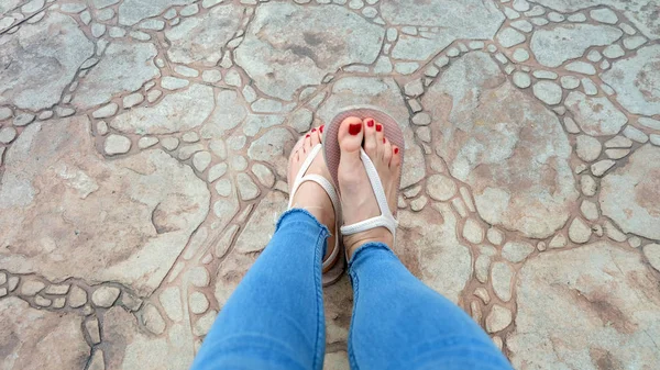 De cerca en los pies de la muchacha con sandalias y pantalones vaqueros azules en el azulejo —  Fotos de Stock