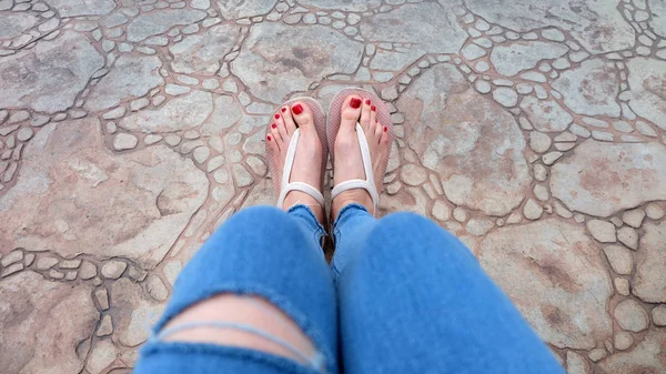 Gros plan sur les pieds de la fille portant des sandales et des jeans bleus sur la tuile — Photo