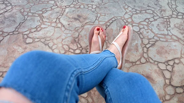 Gros plan sur les pieds de la fille portant des sandales et des jeans bleus sur la tuile — Photo