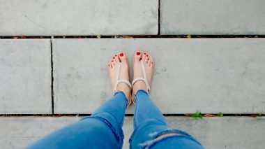 Kadının ayakları üzerinde betonun üzerinde aşınma sandalet yakın çekim