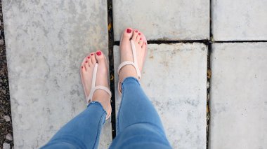 Kadının ayakları üzerinde betonun üzerinde aşınma sandalet yakın çekim