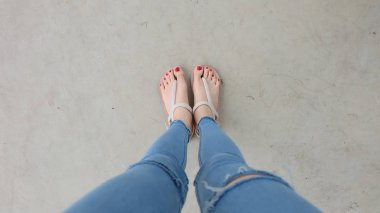 Beton zemin üzerinde sandalet giyen kadın
