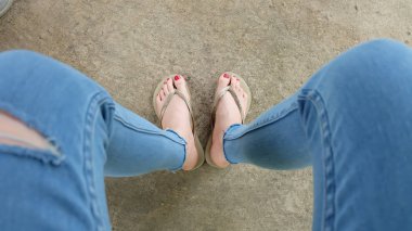 Beton zemin üzerinde sandalet giyen kadın