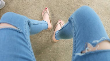 Beton zemin üzerinde sandalet giyen kadın