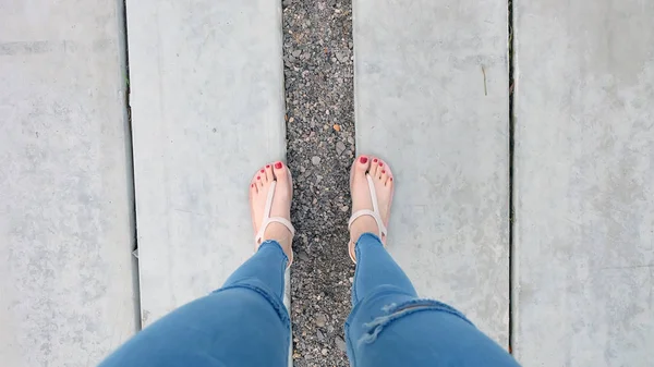 Nahaufnahme an Frauenfüßen trägt Sandalen auf dem Beton — Stockfoto