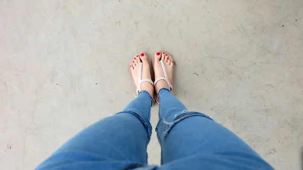 Frau trägt Sandalen auf dem Betonboden — Stockfoto