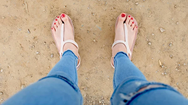 在土壤背景下, 亲密的女孩脚上穿着凉鞋和红指甲 — 图库照片