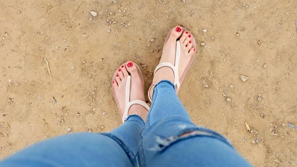 토양 배경에 샌들과 빨간 손톱을 착용 하는 여자의 발에 닫기 — 스톡 사진