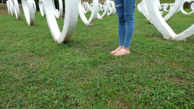 Beyaz kalp şekli yapay arka plan ile yeşil çimenlerin üzerinde duran sandaletler içinde ayak Selfie