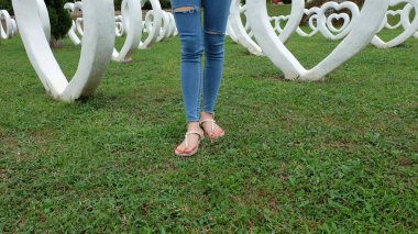 Beyaz kalp şekli yapay arka plan ile yeşil çimenlerin üzerinde duran sandaletler içinde ayak Selfie
