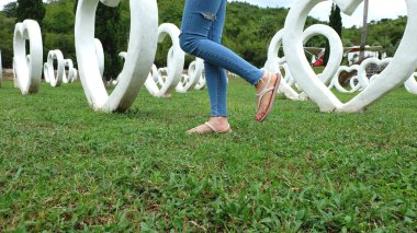 Beyaz kalp şekli yapay arka plan ile yeşil çimenlerin üzerinde duran sandaletler içinde ayak Selfie