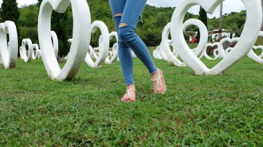 Beyaz kalp şekli yapay arka plan ile yeşil çimenlerin üzerinde duran sandaletler içinde ayak Selfie