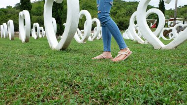 Beyaz kalp şekli yapay arka plan ile yeşil çimenlerin üzerinde duran sandaletler içinde ayak Selfie