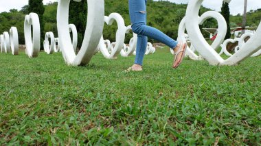 Beyaz kalp şekli yapay arka plan ile yeşil çimenlerin üzerinde duran sandaletler içinde ayak Selfie