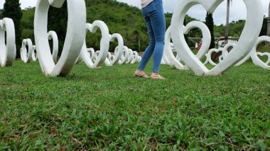 Beyaz kalp şekli yapay arka plan ile yeşil çimenlerin üzerinde duran sandaletler içinde ayak Selfie