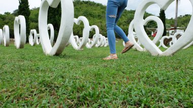 Beyaz kalp şekli yapay arka plan ile yeşil çimenlerin üzerinde duran sandaletler içinde ayak Selfie