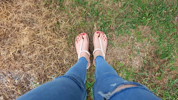 Selfie stopy w sandałach, stojący na zielonej trawie i sucha trawa tło — Zdjęcie stockowe