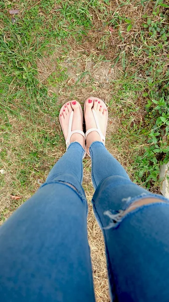 Füße-Selfie in goldenen Sandalen auf grünem Gras-Hintergrund — Stockfoto