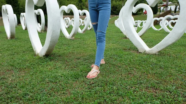 Fötter Selfie i sandaler står på grönt gräs med vitt hjärta form konstgjorda bakgrund — Stockfoto