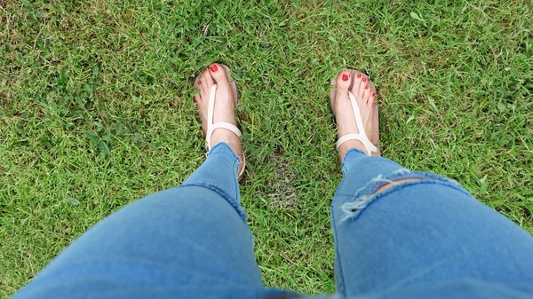 Selfie de pies en sandalias de oro de pie sobre fondo de hierba verde — Foto de Stock