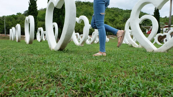 Beyaz kalp şekli yapay arka plan ile yeşil çimenlerin üzerinde duran sandaletler içinde ayak Selfie