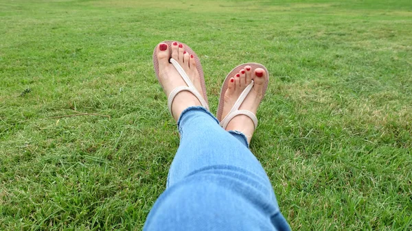 Füße-Selfie in goldenen Sandalen auf grünem Gras-Hintergrund — Stockfoto