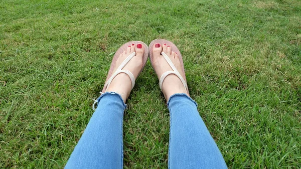 Füße-Selfie in goldenen Sandalen auf grünem Gras-Hintergrund — Stockfoto